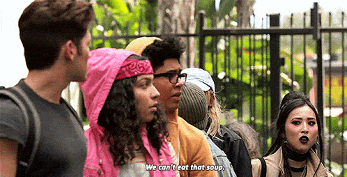 a group of people are standing in front of a fence and one of them is saying `` we can 't eat that soup . ''