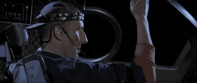 a man wearing a helmet and a headset is giving the thumbs up