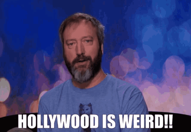 a man with a beard wearing a blue shirt says " hollywood is weird "