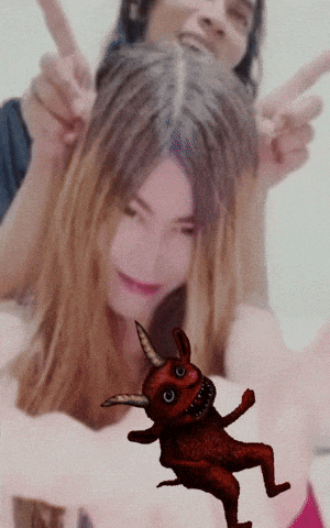 a man and a woman are giving a peace sign with a devil in the background