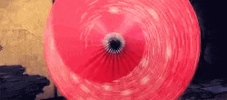 a close up of a red umbrella with a hole in the middle spinning in the air .