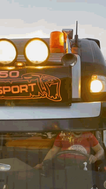 a man is driving a truck with a sign that says sport