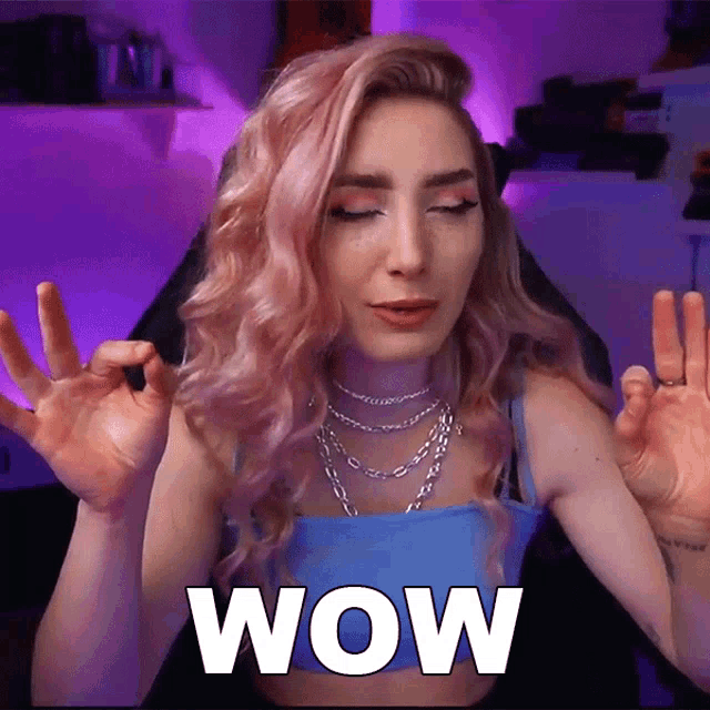 a woman with pink hair is making a wow gesture with her hands