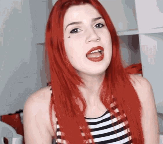 a woman with red hair is wearing a striped top