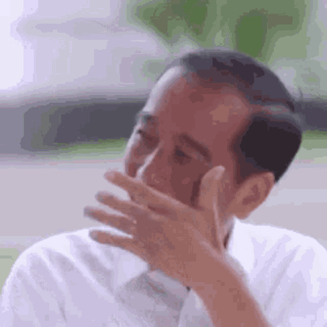 a man is covering his mouth with his hand .