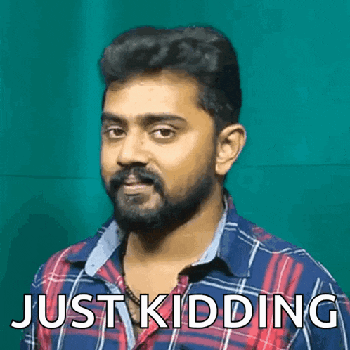 a man with a beard is wearing a plaid shirt and the words just kidding are above him