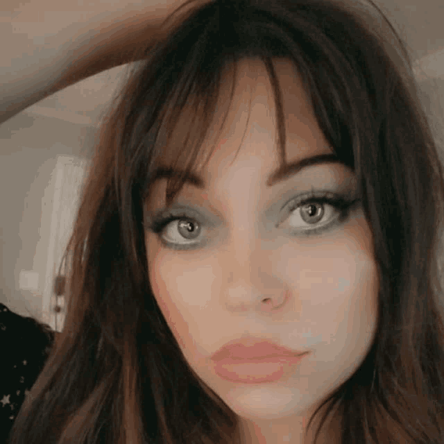 a close up of a woman 's face with her hand on her hair