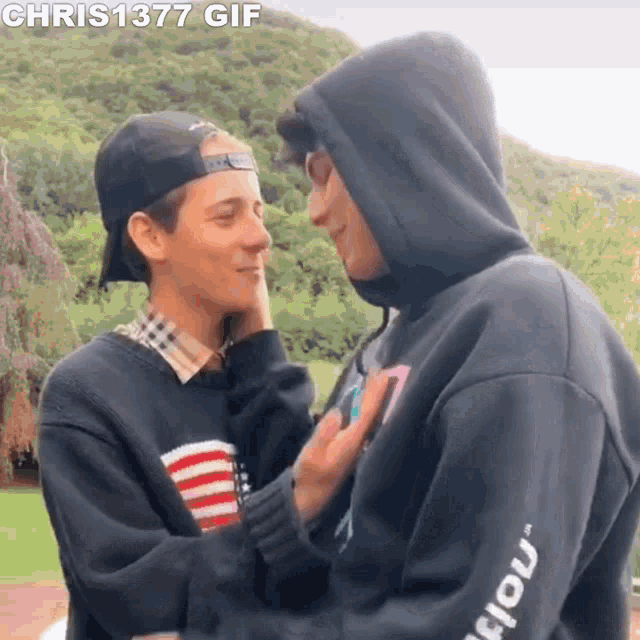 two young men are looking at each other and touching their faces .