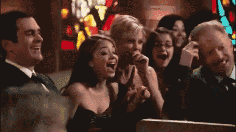 a group of people are laughing in a church while sitting in a pew .