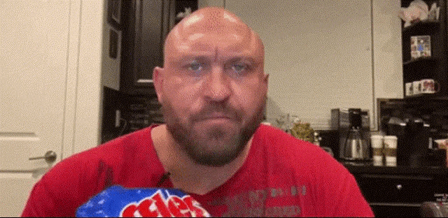 a bald man with a beard is holding a bag of chips .