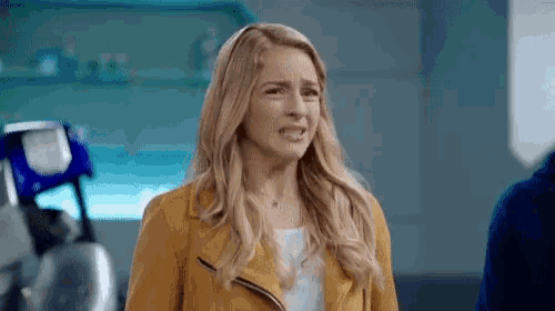 a woman in a yellow jacket is making a face .