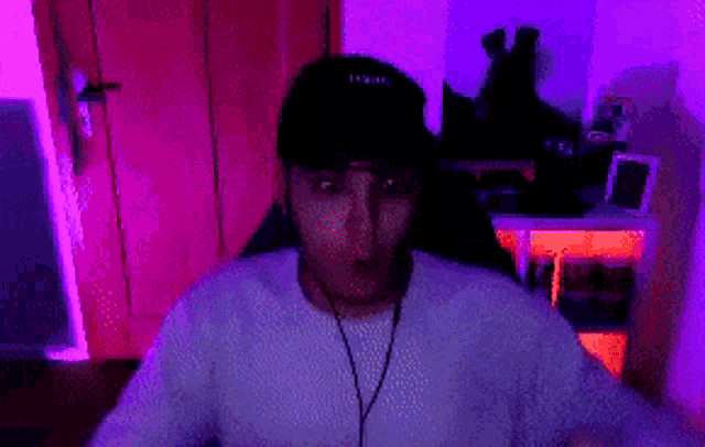 a man wearing a hat and a white shirt is sitting in front of a computer screen