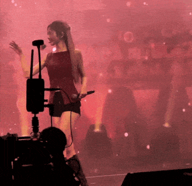 a woman singing into a microphone in front of a red background with the number 10 on it