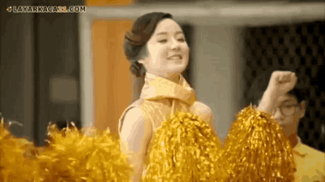 a woman in a gold dress is holding gold pom poms
