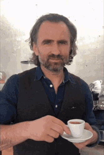 a man with a beard is holding a cup of coffee in his hand