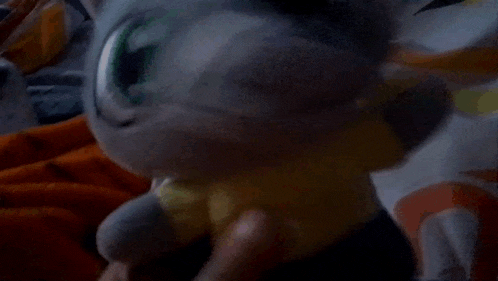 a stuffed animal with green eyes is laying on a blanket on a bed .