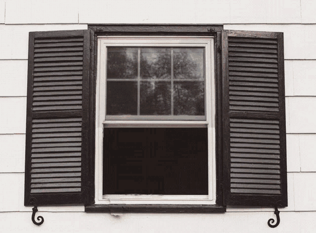 a window with black shutters on it and a swirl on the side
