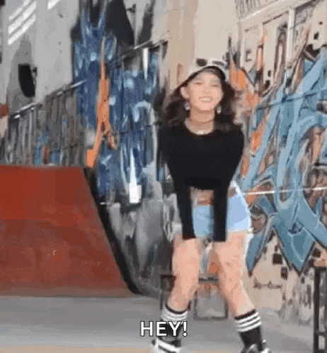 a girl is standing in front of a wall with graffiti on it while wearing roller skates .