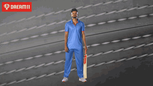 a man in a blue shirt is holding a cricket bat in front of a sign that says dream11