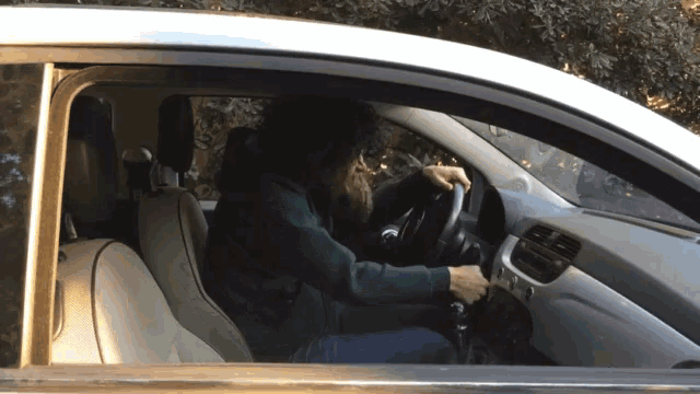 a woman in a green sweater is sitting in a car