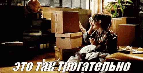 a woman sits on the floor surrounded by moving boxes with the words " это так трогательно " in white letters