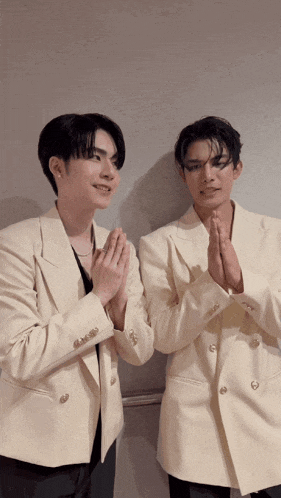two men wearing white suits are praying together