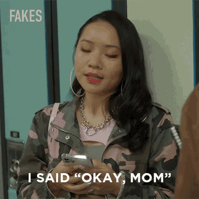 a woman holding a cell phone with fakes written on the bottom