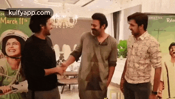 three men are standing next to each other in a room .