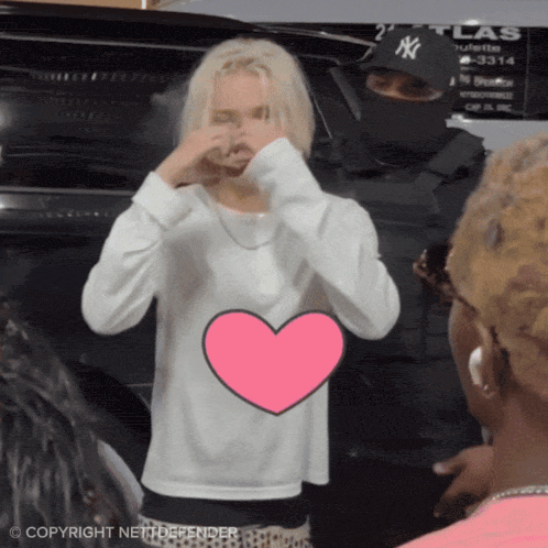 a woman in a white sweater with a pink heart in front of her