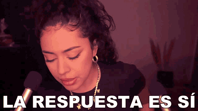 a woman stands in front of a microphone with the words la respuesta es si below her