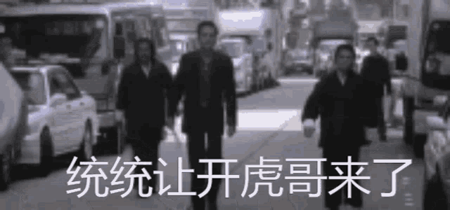 a group of men are walking down a street with chinese writing