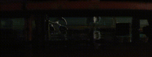 a person is sitting in a dark room looking out a window at night .