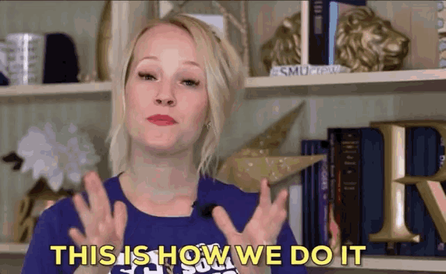 a woman says " this is how we do it " in front of a bookshelf