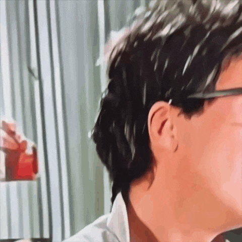 a close up of a man 's face with glasses and a red liquid in his hand .