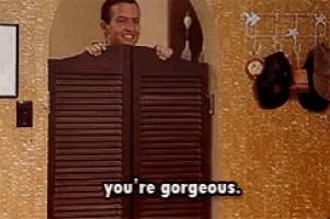 a man is peeking out from behind a pair of saloon doors and saying you 're gorgeous .