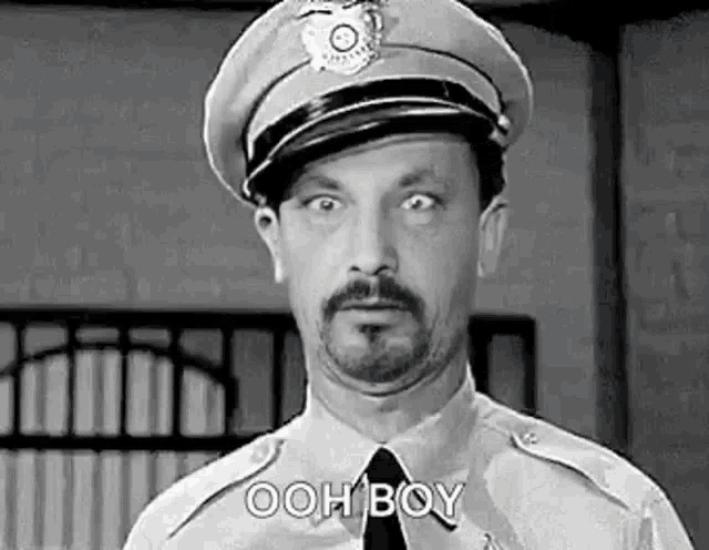 a black and white photo of a police officer with a beard .