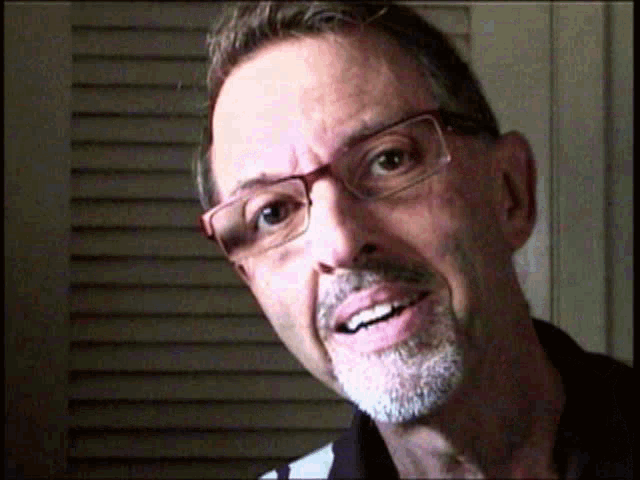 a close up of a man wearing glasses and a beard