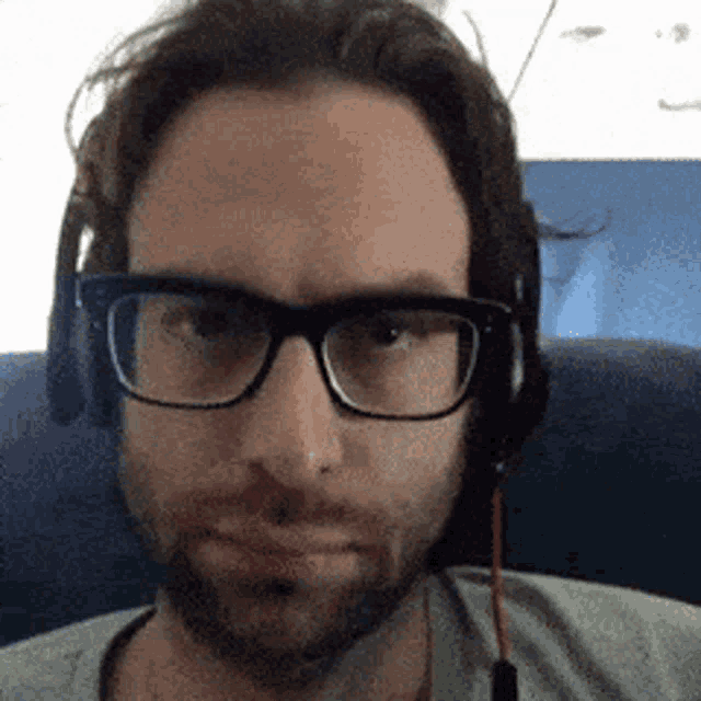 a man wearing glasses and headphones is sitting on a plane