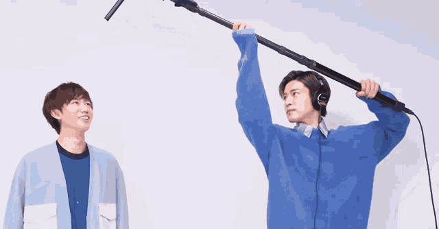 a man in a blue sweater is holding a microphone in his hand