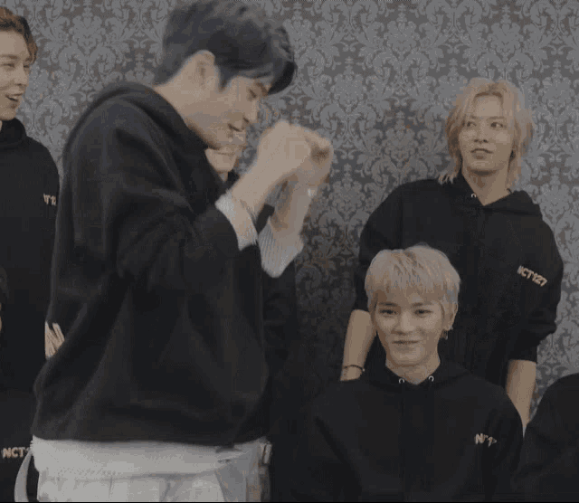 a group of young men wearing black hoodies with nct 127 on the front