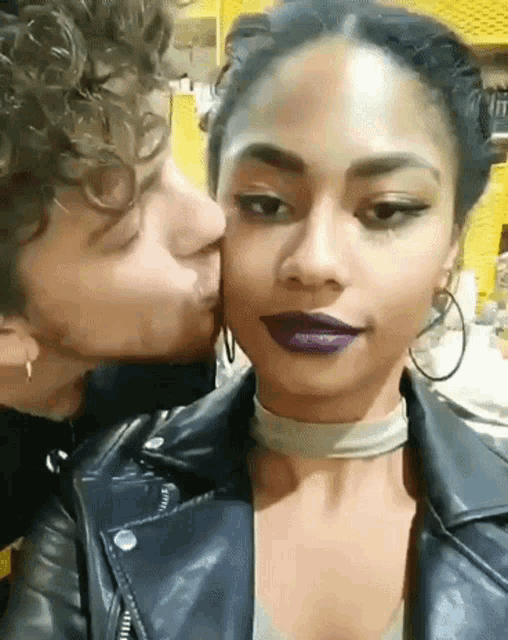 a man is kissing a woman on the cheek while wearing purple lipstick