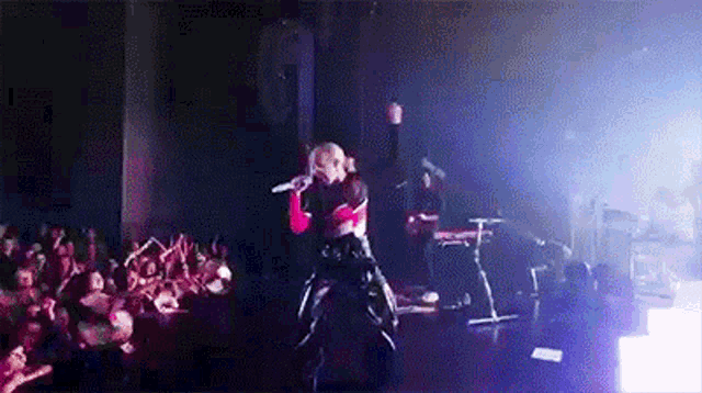 a woman is singing into a microphone on a stage in front of a crowd