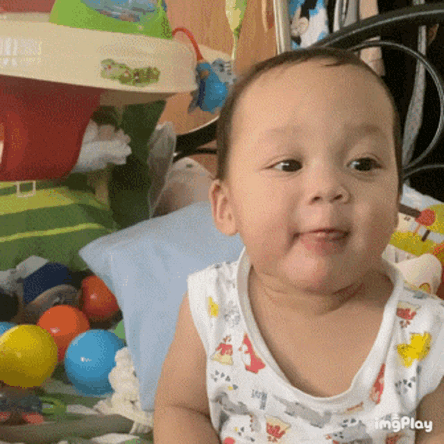 a baby wearing a white tank top with animals on it is smiling for the camera