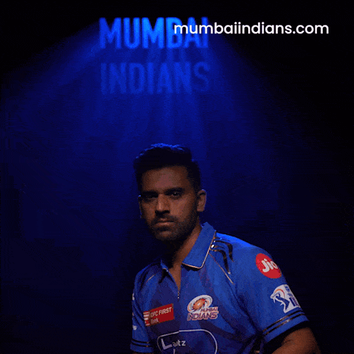 a man in a blue shirt stands in front of a blue background that says mumbai indians