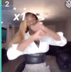 a woman is dancing in a living room with her hands crossed .
