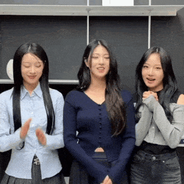 three women standing next to each other with their hands folded in front of them