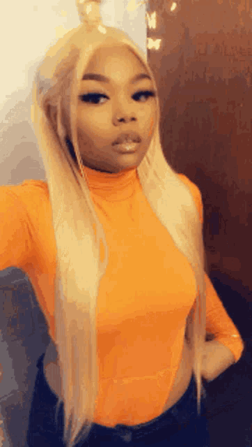 a woman with blonde hair is taking a selfie in a bright orange top .