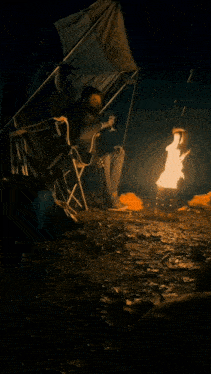 a man sits in a chair in front of a fire
