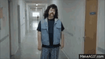 a man with a beard is walking down a hallway .