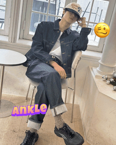 a man in a denim jacket is sitting on a chair with the word ankle above his feet